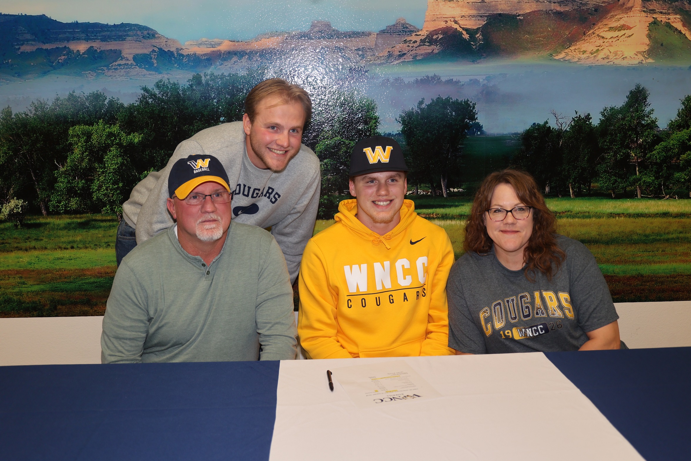 Carter Reisig (middle) smiles after signing to play for WNCC next year.